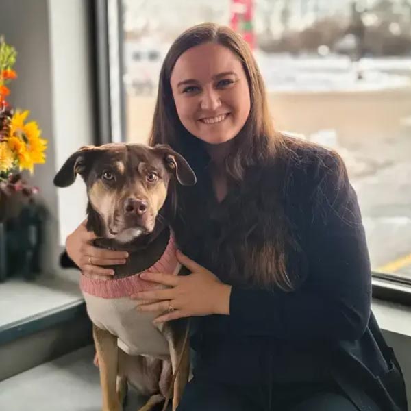 Emmy smiling and hugging dog