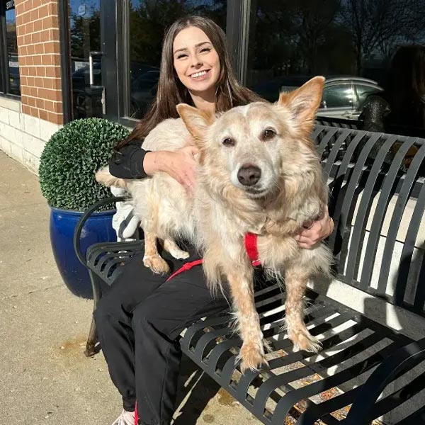 Kiley smiling while sitting outdoors with a dog