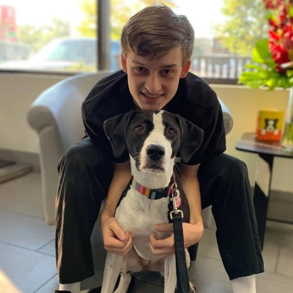Luke smiling and hugging black and white dog