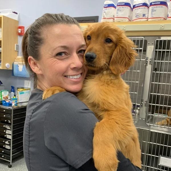 Melanie smiling and holding golden retriever puppy