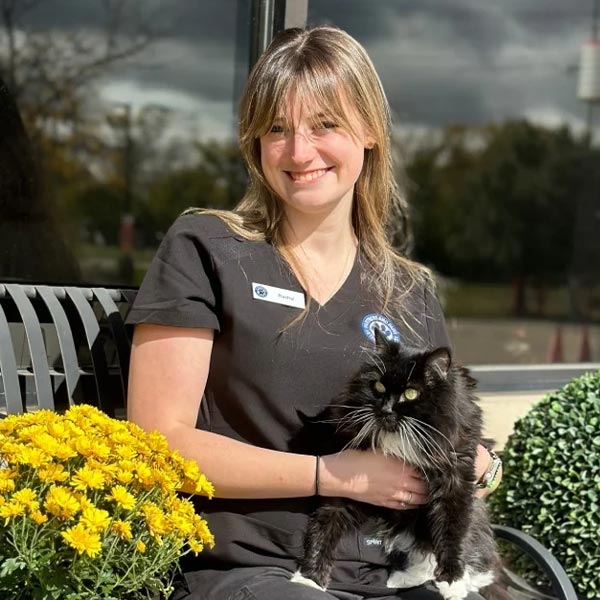 Rachel smiling while sitting outsite holding tuxedo cat